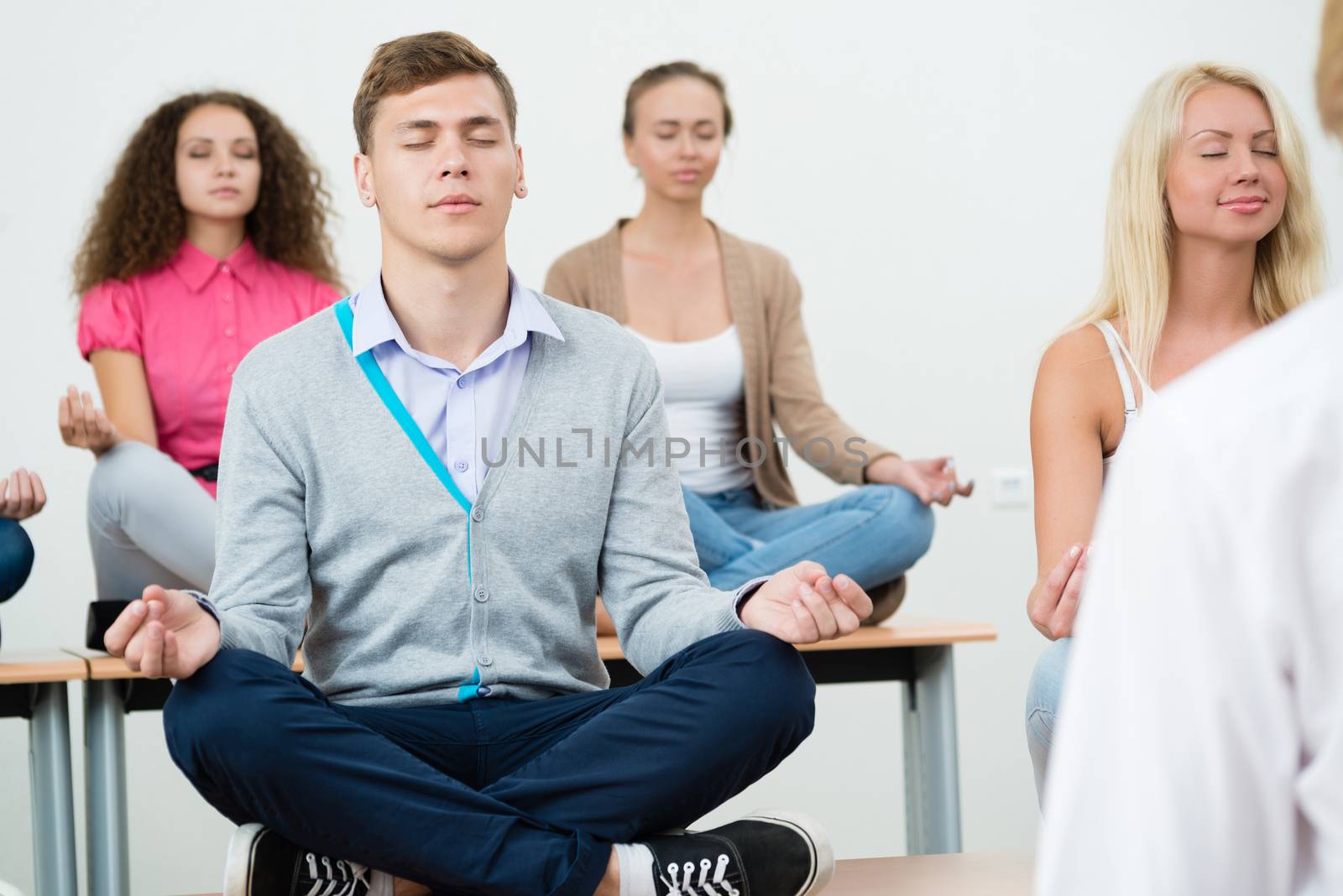 group of young people meditating in office at desk, group meditation