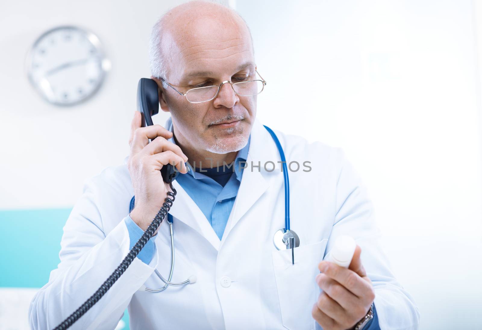 Doctor talking on the phone and looking at medicine's bottle.