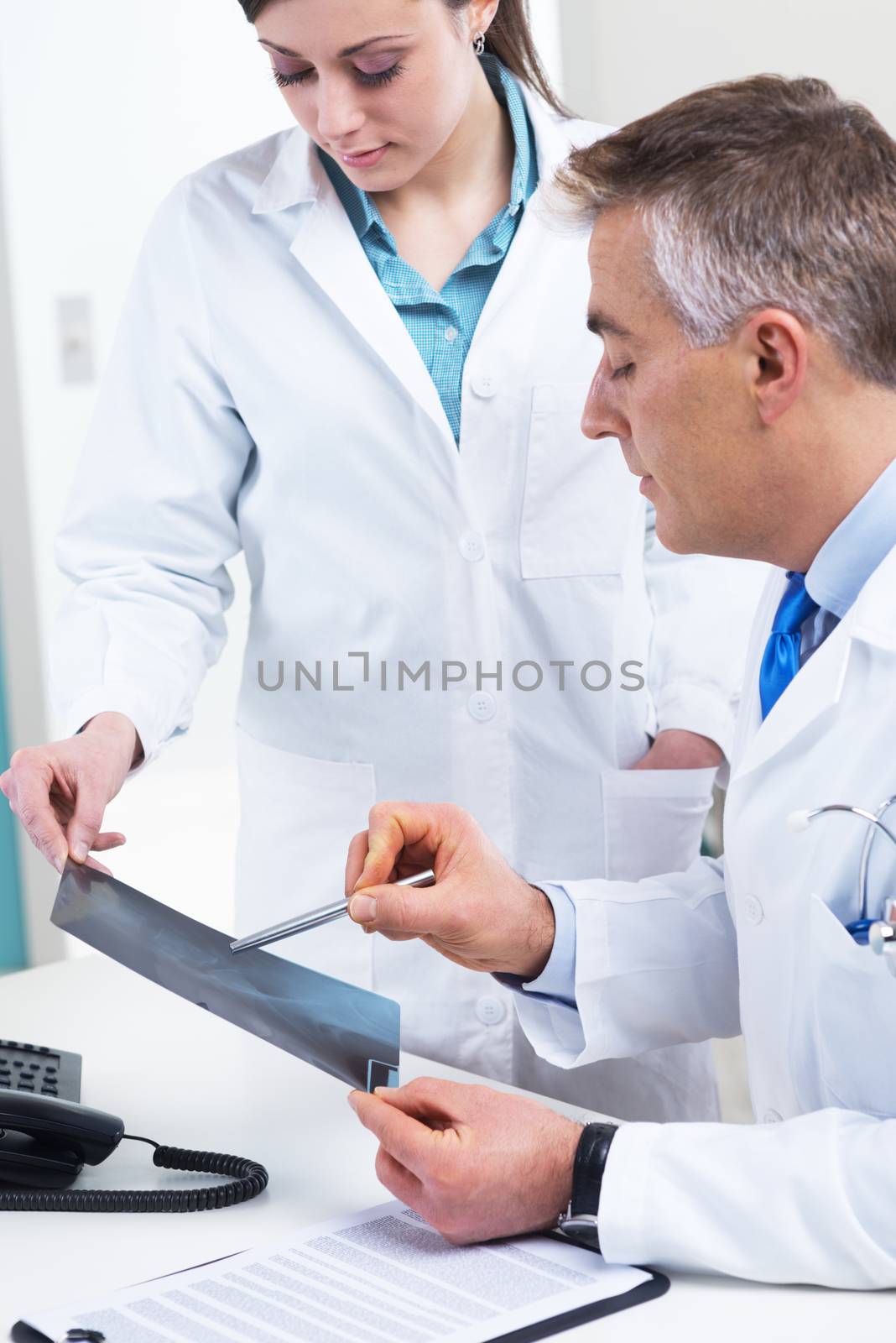 Medical team examining an x-ray image and pointing with a pen.