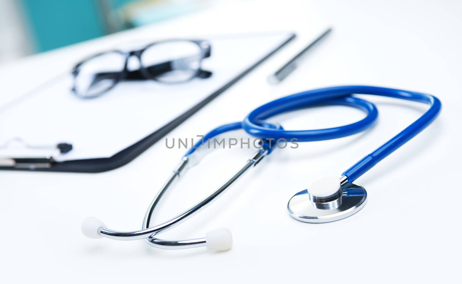 Medical equipment: blue stethoscope, clipboard, pen and glasses.