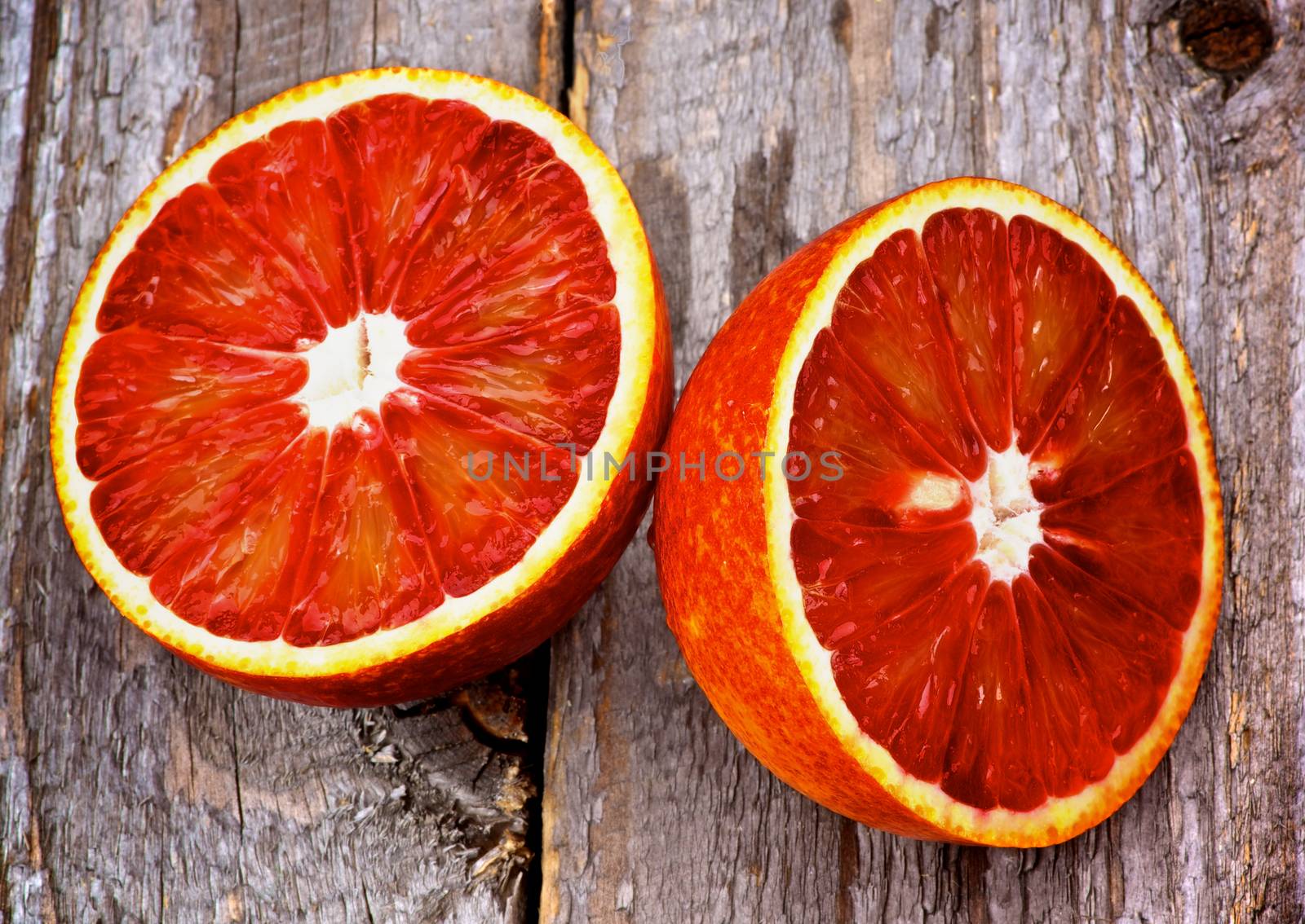 Halves of Ripe Raw Blood Orange closeup on Rustic Wooden background