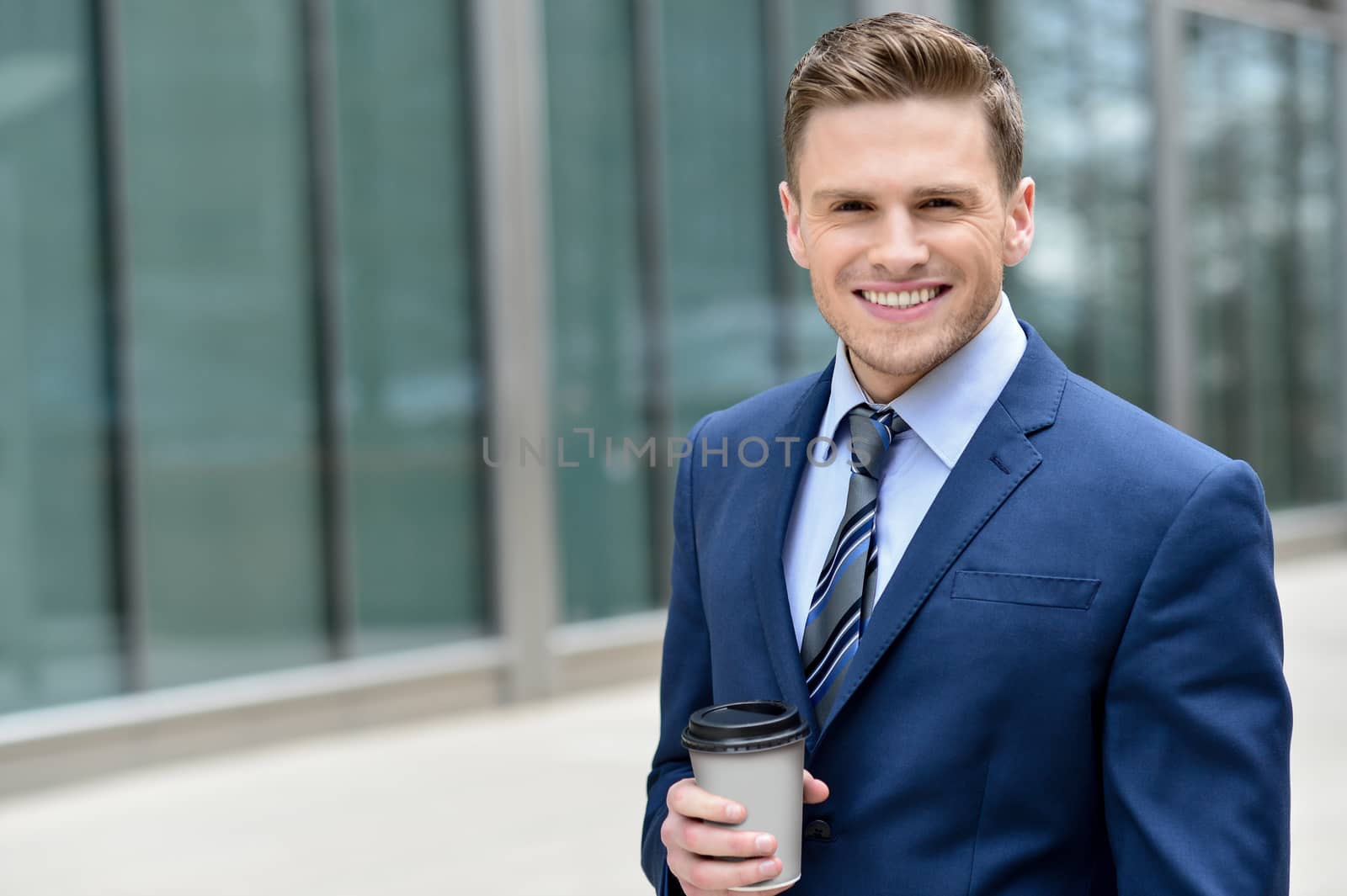 Smiling businessman with coffee sipper by stockyimages