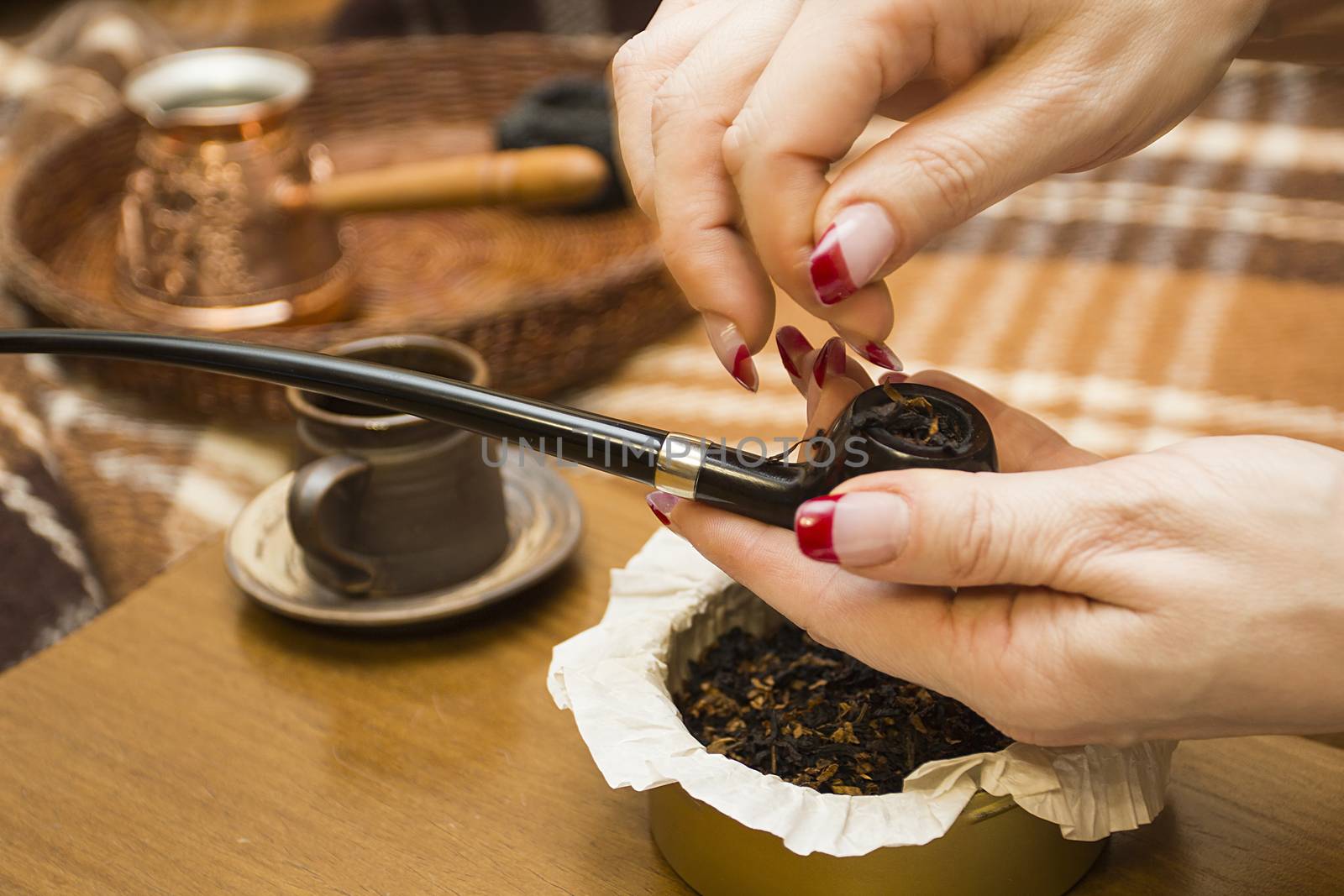 Female hand tamping tobacco smoking pipe.