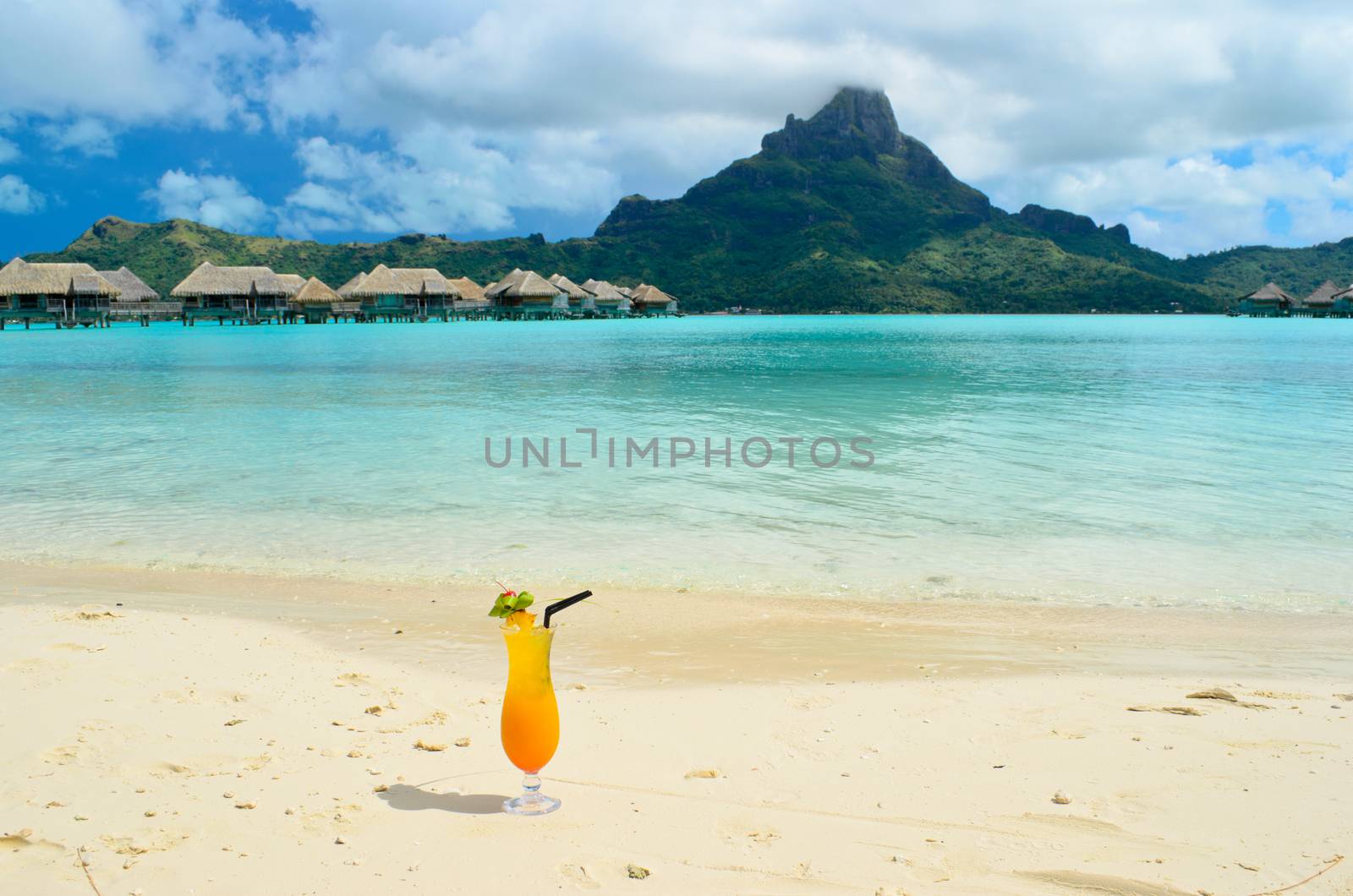 Sex on the beach cocktail on the beach of a luxury vacation resort in the lagoon with a view on the tropical island of Bora Bora, near Tahiti, in French Polynesia.