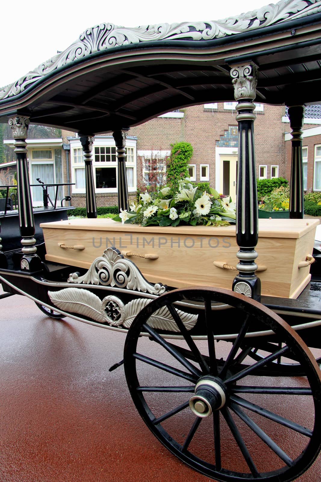 Wooden casket with funeral flowerson a funeral carriage