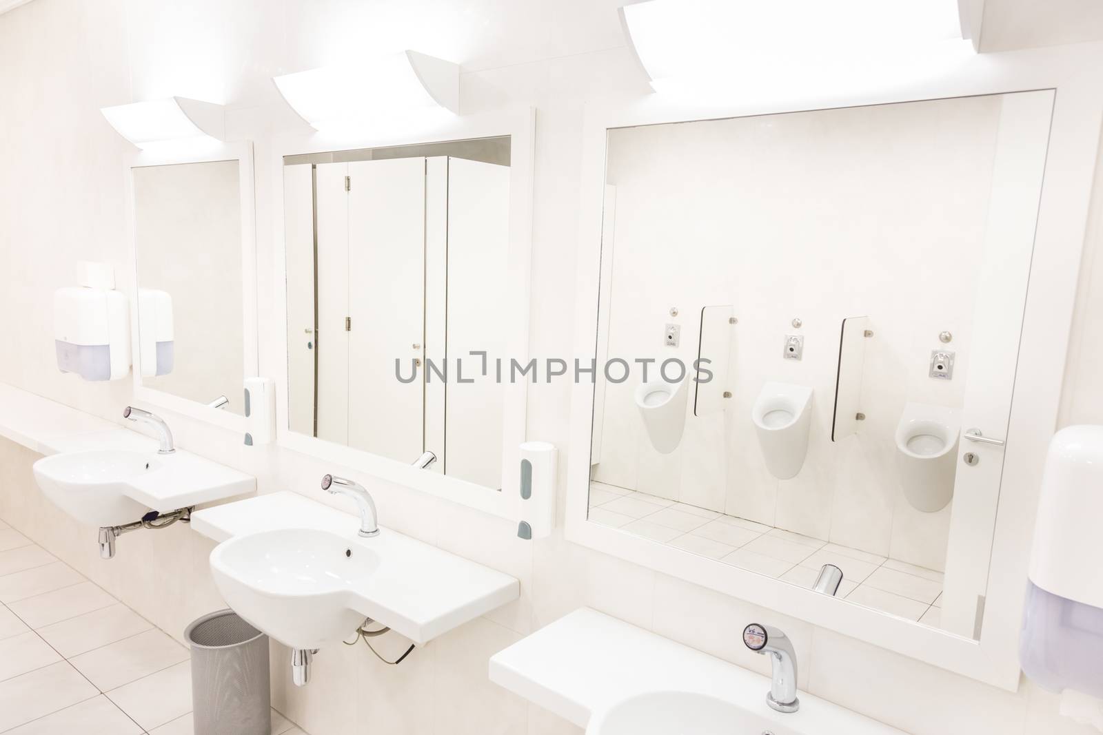 Public empty white man restroom with washstands mirrors.