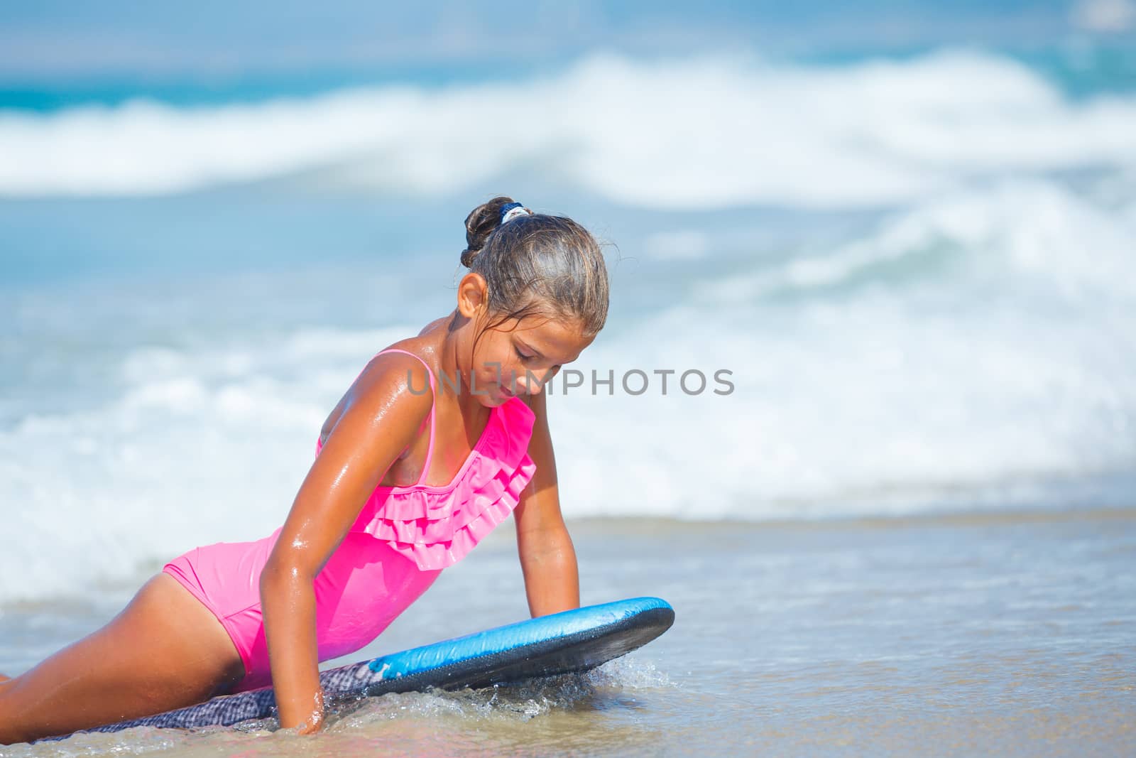 Summer vacation - Happy cute girl having fun with surfboard in the ocean
