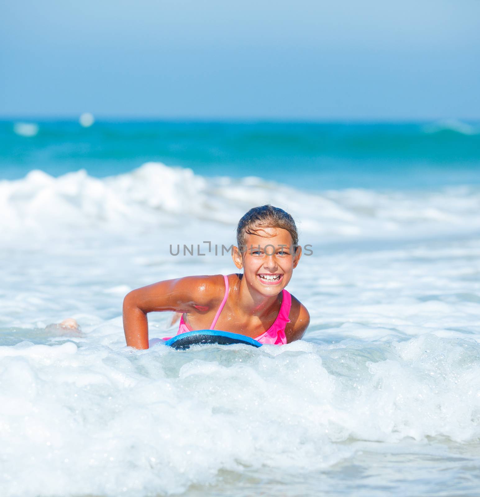 Summer vacation - Happy cute girl having fun with surfboard in the ocean