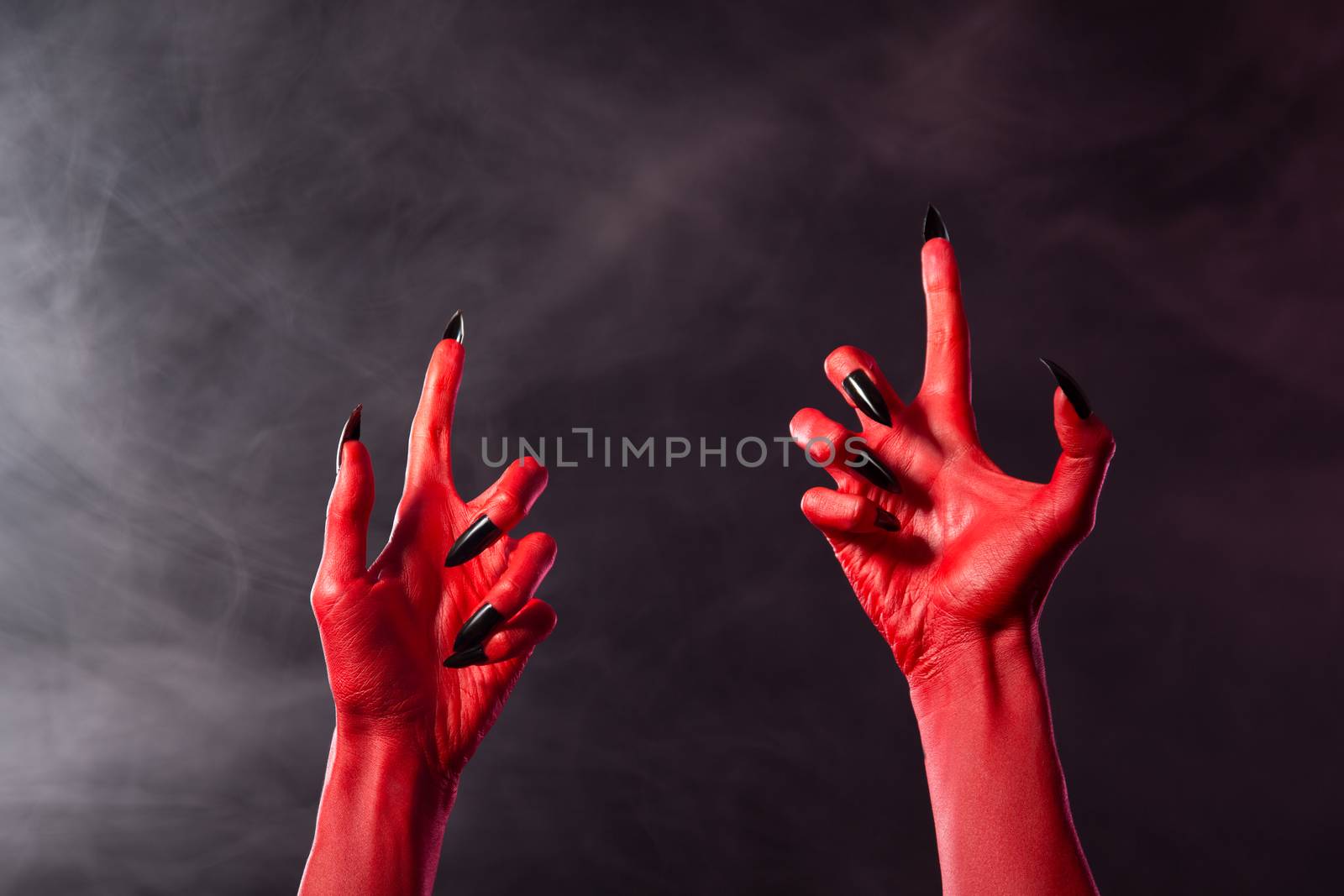 Creepy red devil hands with black sharp nails, Halloween theme  