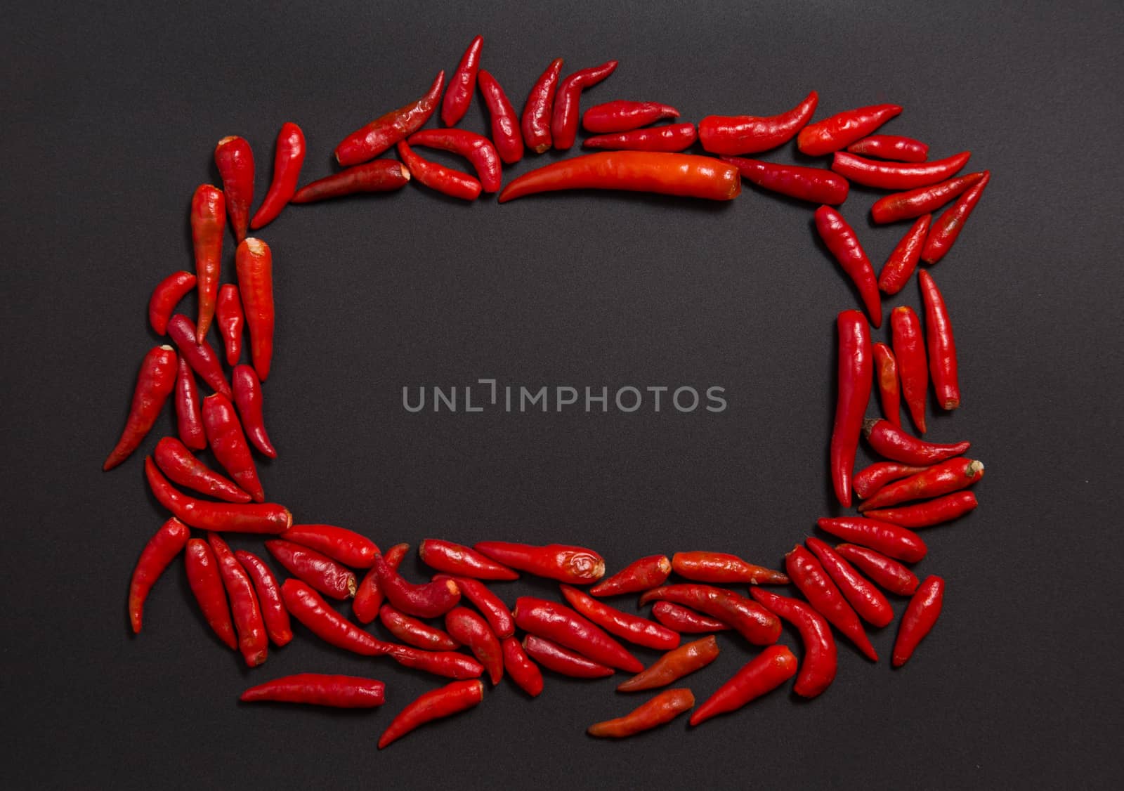 Frame made of non-stem red bird eye chili peppers on grey background 