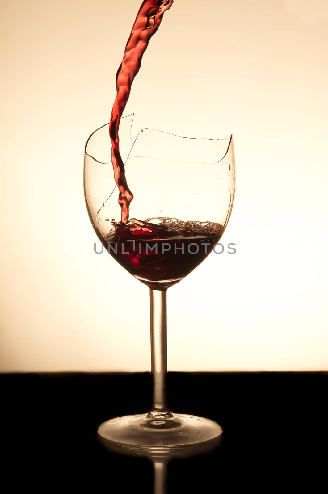 Pouring red vine into a broken glass