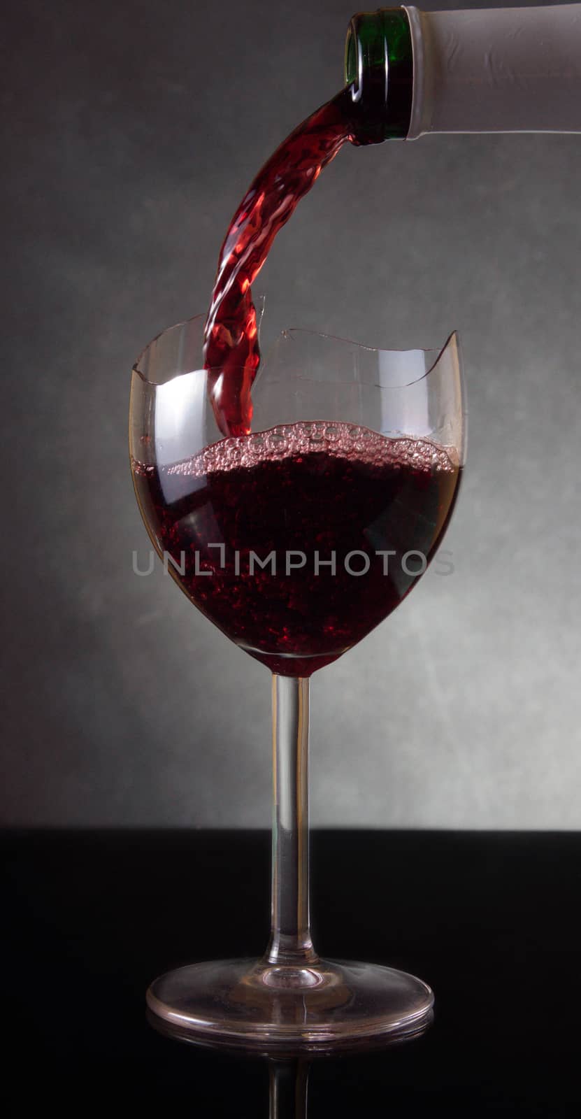 Pouring red vine into a broken glass