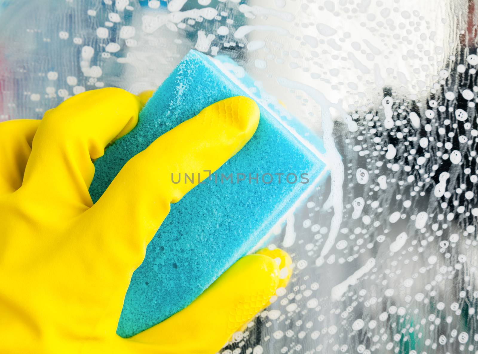 Hand in yellow protective glove cleaning glass with sponge
