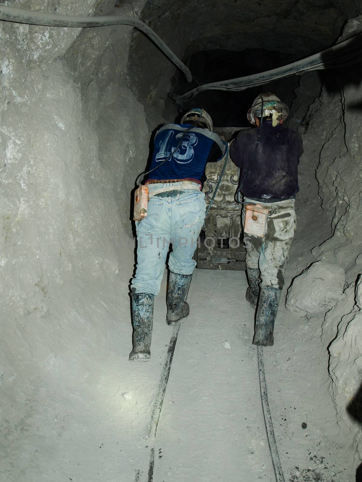 Two miners push the mining truck in Potosi silver mines