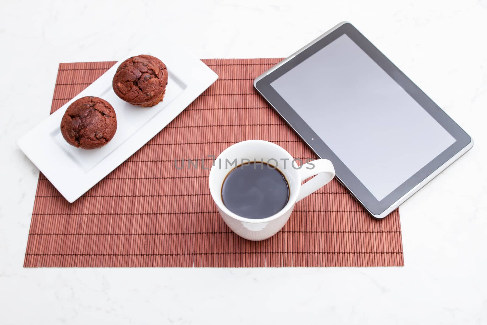 Chocolate chips Muffins with  a cup of coffee meanwhile using the tablet PC.