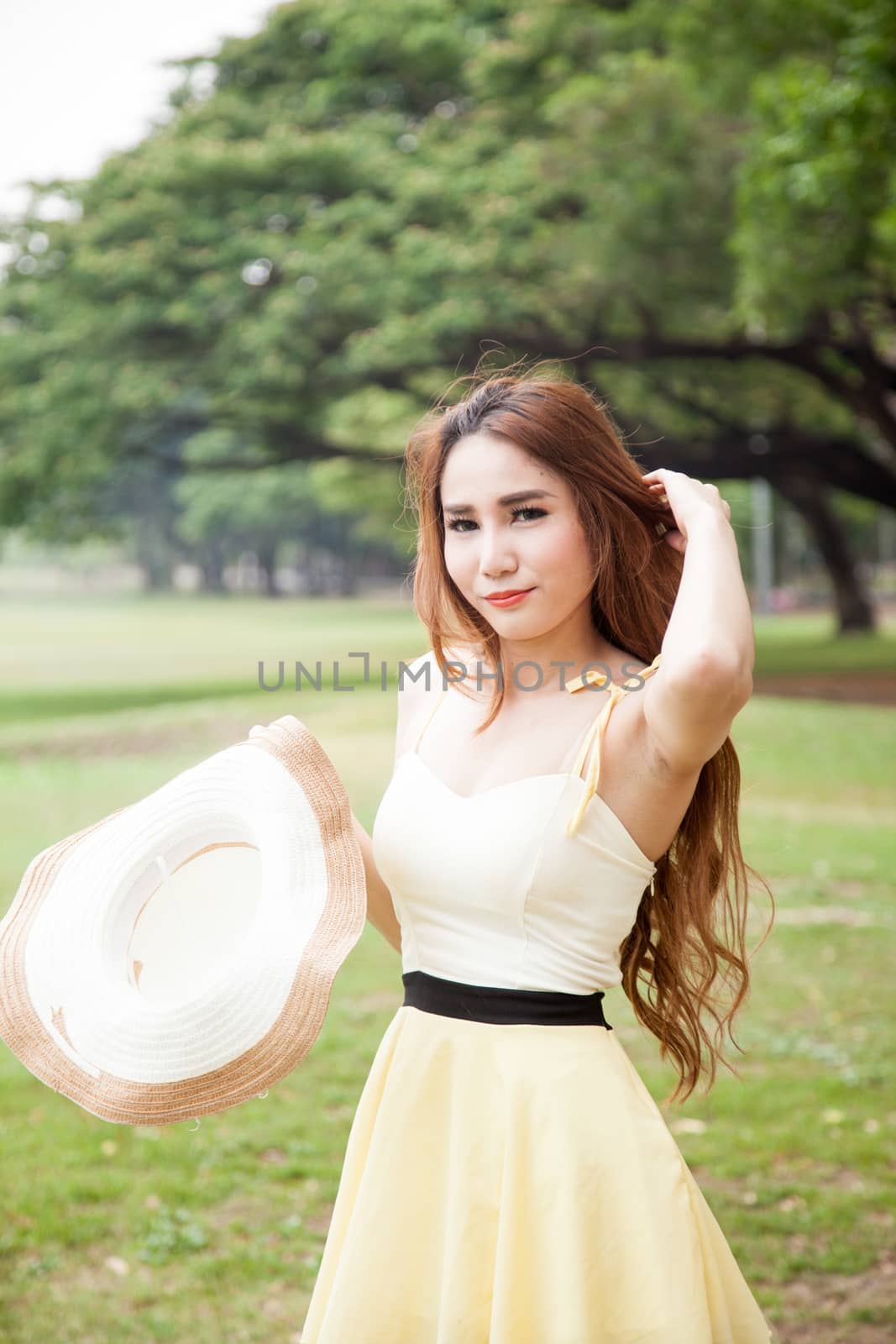 Woman holding a hat. Located at the lawn in the park.