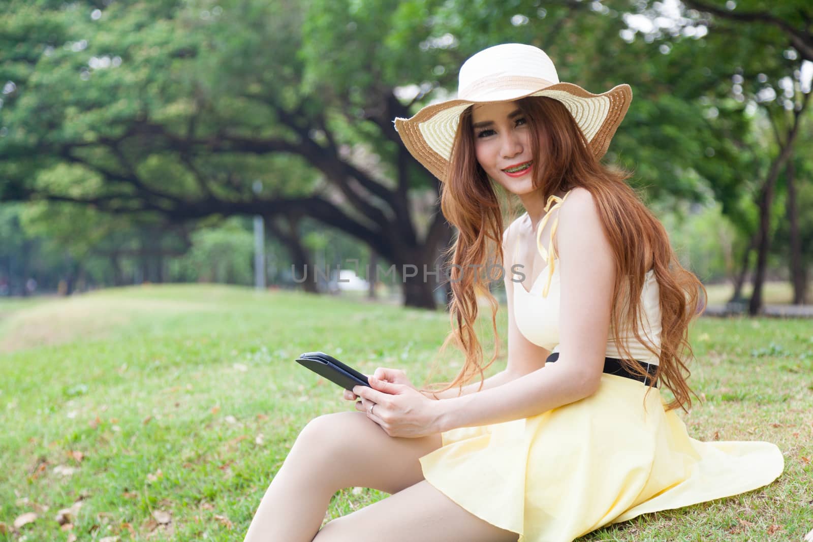 Woman sitting on grass and using a tablet. by a454