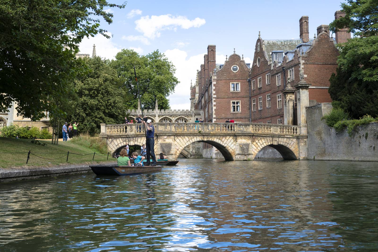 CAMBRIDGE, UK - AUGUST 18: Turist punter in River Cam with tree lined bank to one side and the olderst bridge in Cambridge, Claire bridge, followed by the Bridge of Sights in the far horizon. August 18, 2013 in Cambridge.
