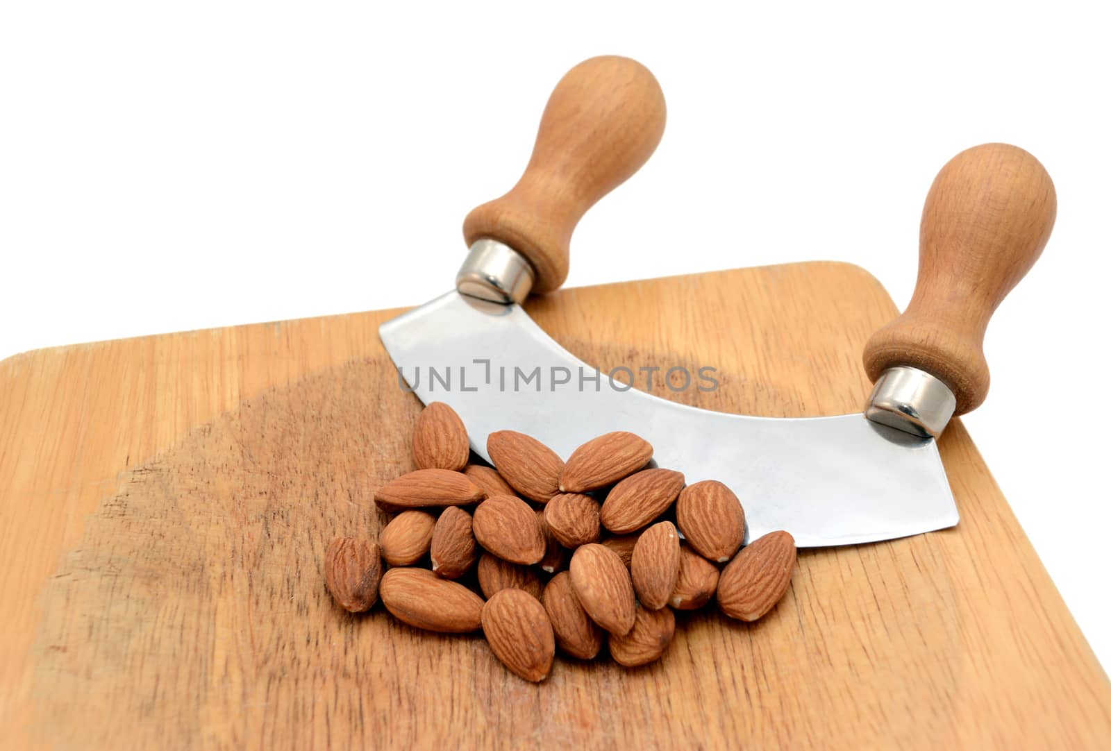 Whole almonds with a rocking knife on a wooden chopping board