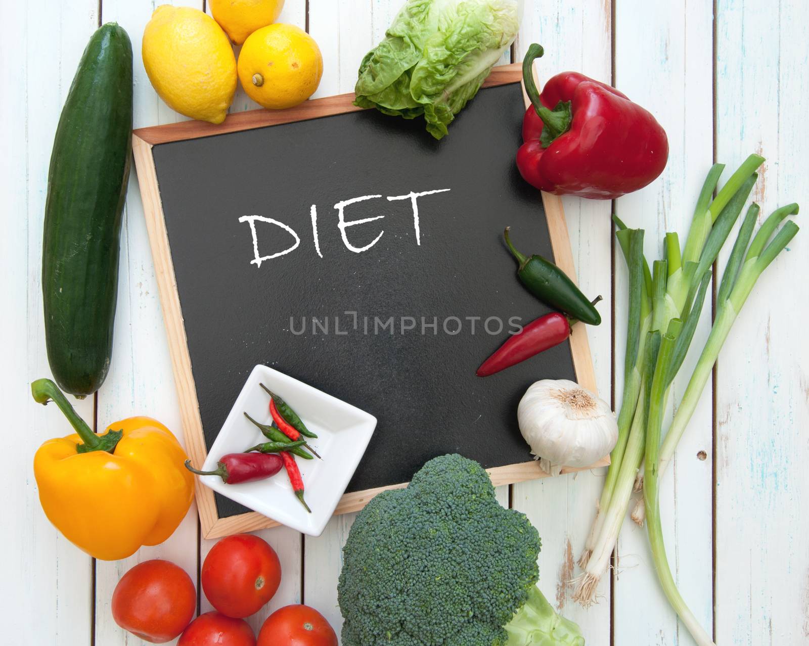 Diet handwritten on a chalkboard surrounded by fresh vegetables 