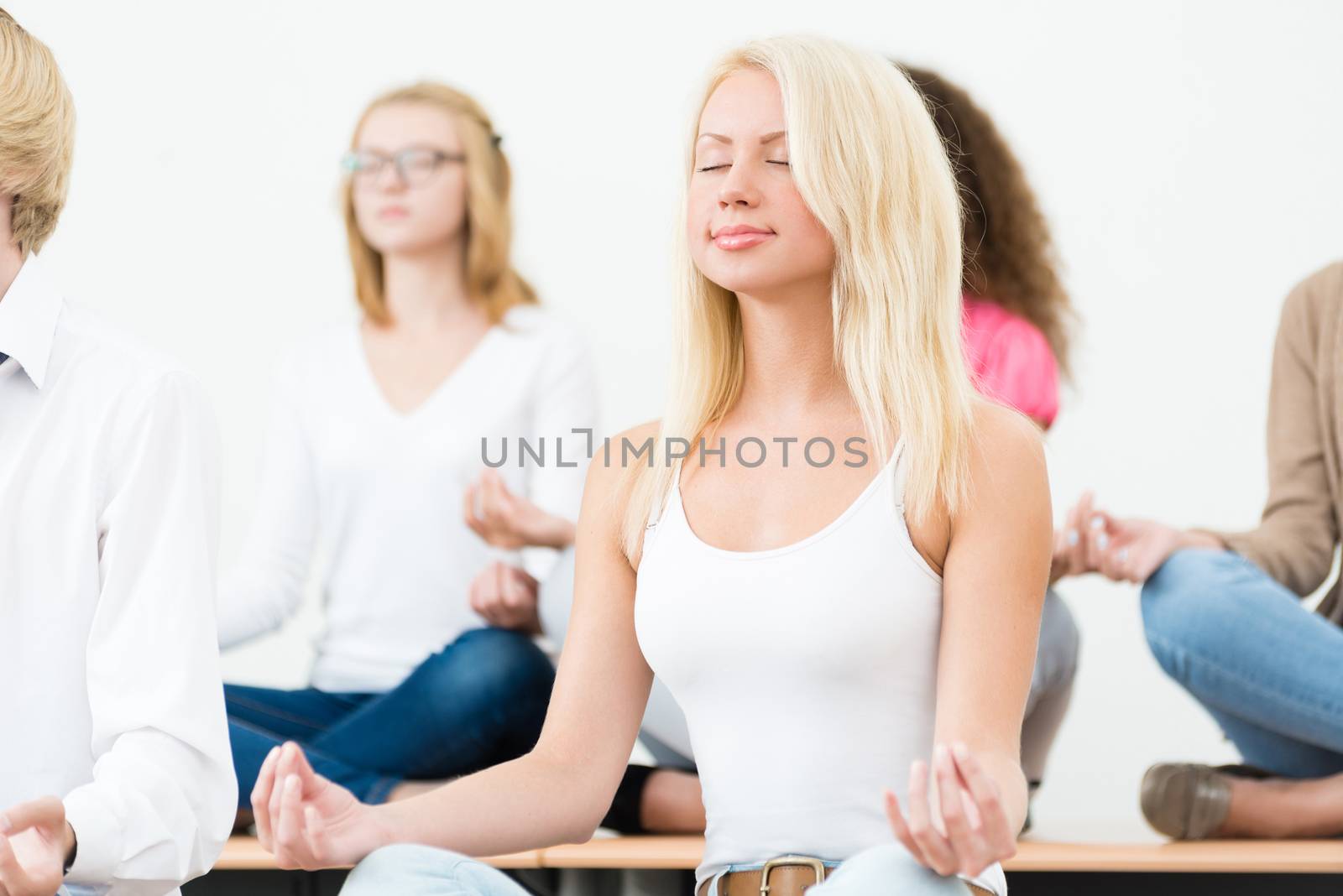 attractive young woman, meditating with closed eyes, group meditation