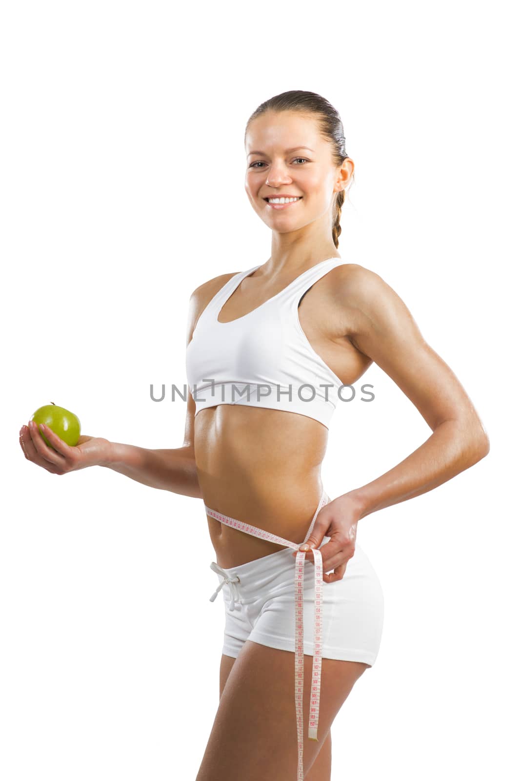 young athletic girl measuring waist measuring tape and holding a green apple, concept of healthy eating, isolated on white background