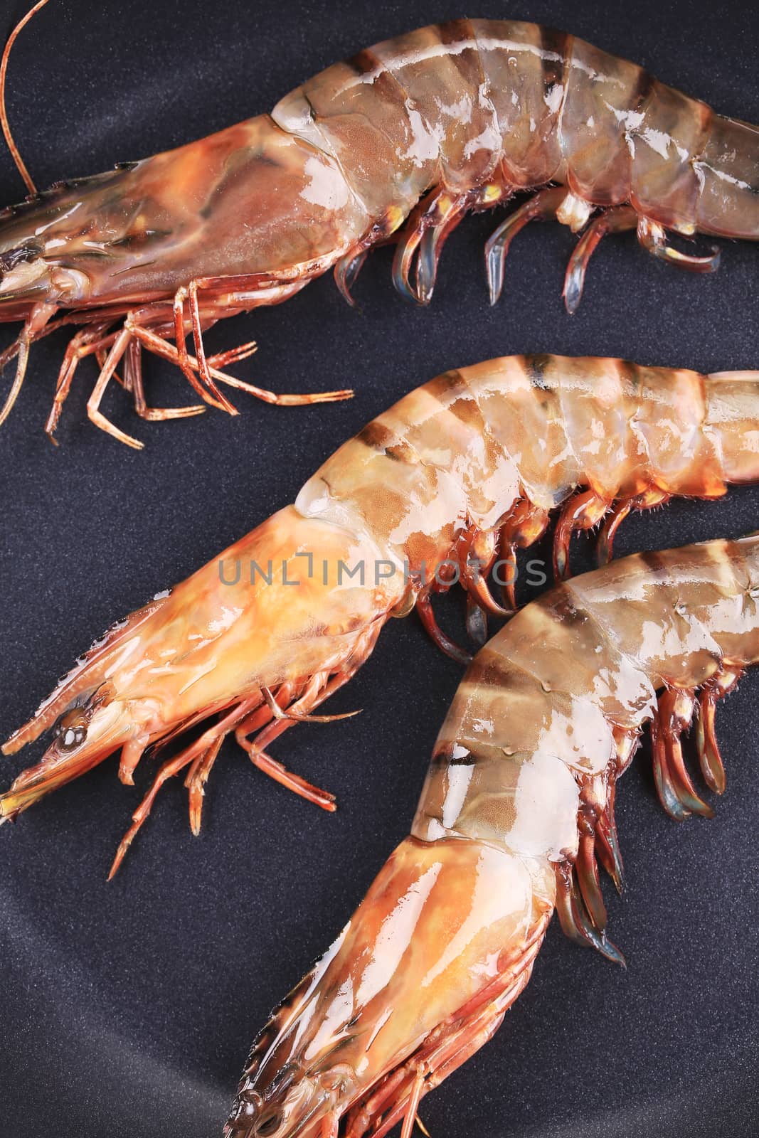 Tiger shrimps on black pan. Whole background.
