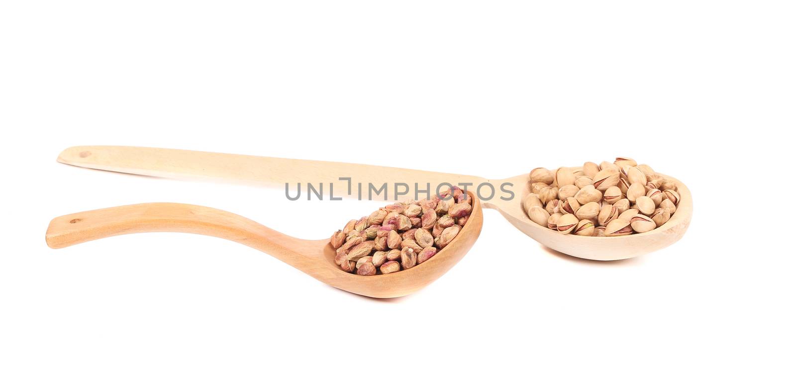 Wooden spoons of pistachios with shell and without. Isolated on a white background.