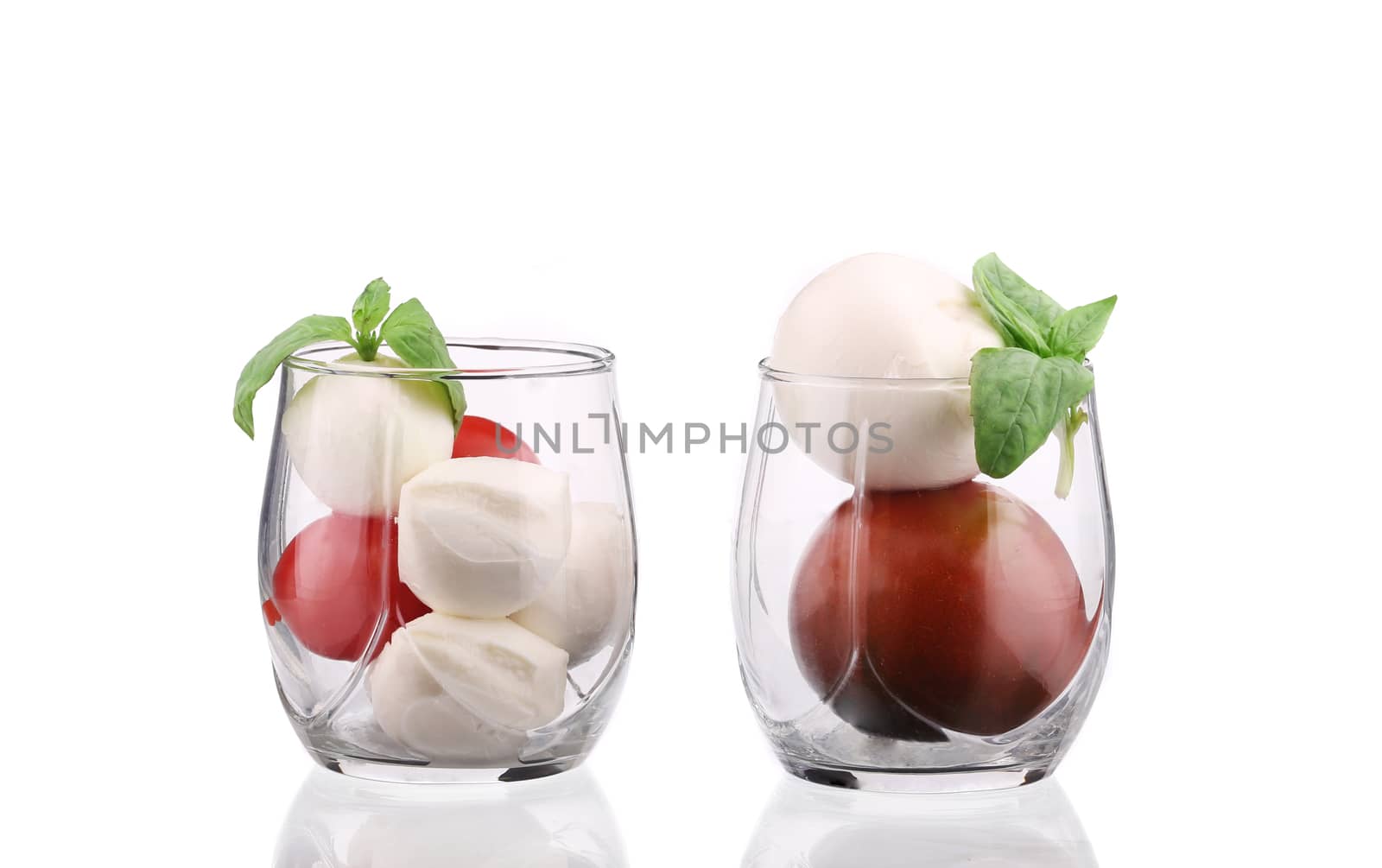 Tomatoes and mozzarella balls in glass. Isolated on a white background.