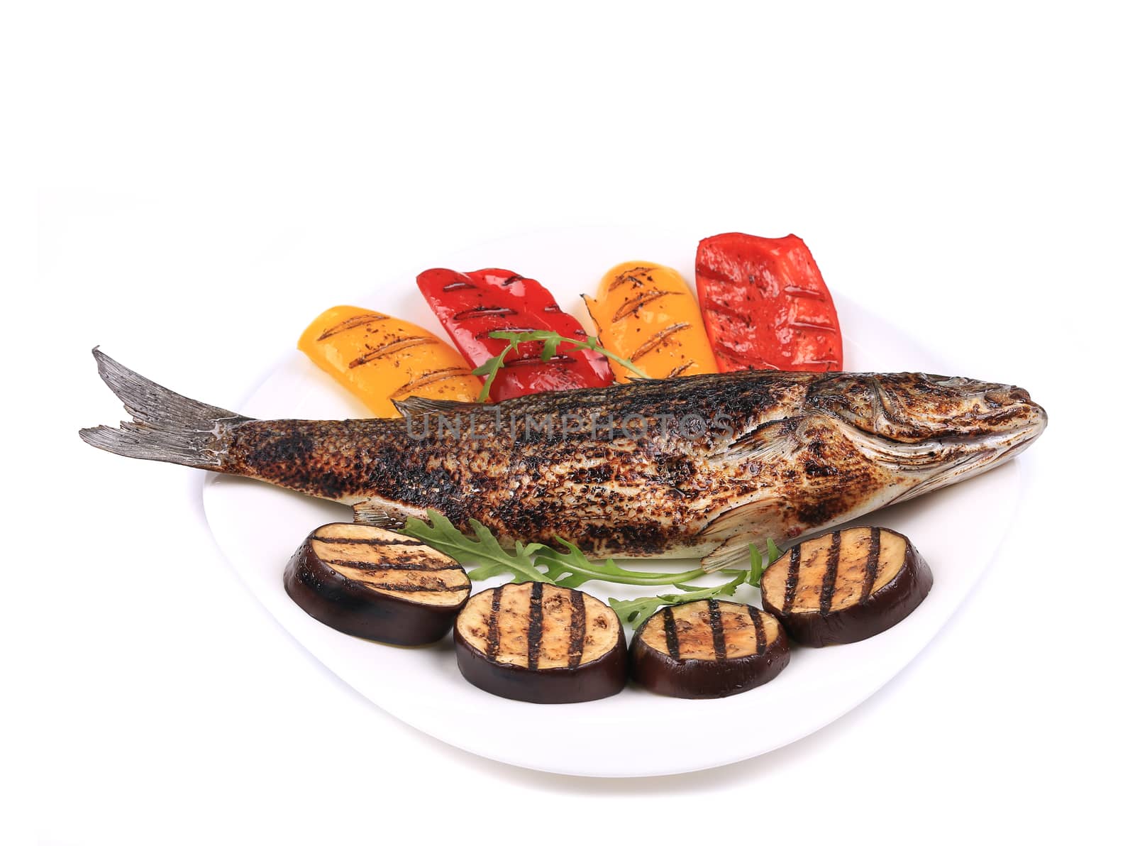 Grilled seabass with vegetables on plate. Isolated on a white background.