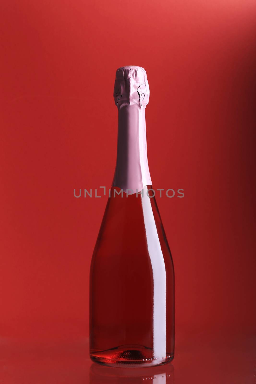 Bottle of pink champagne. Whole pink background.