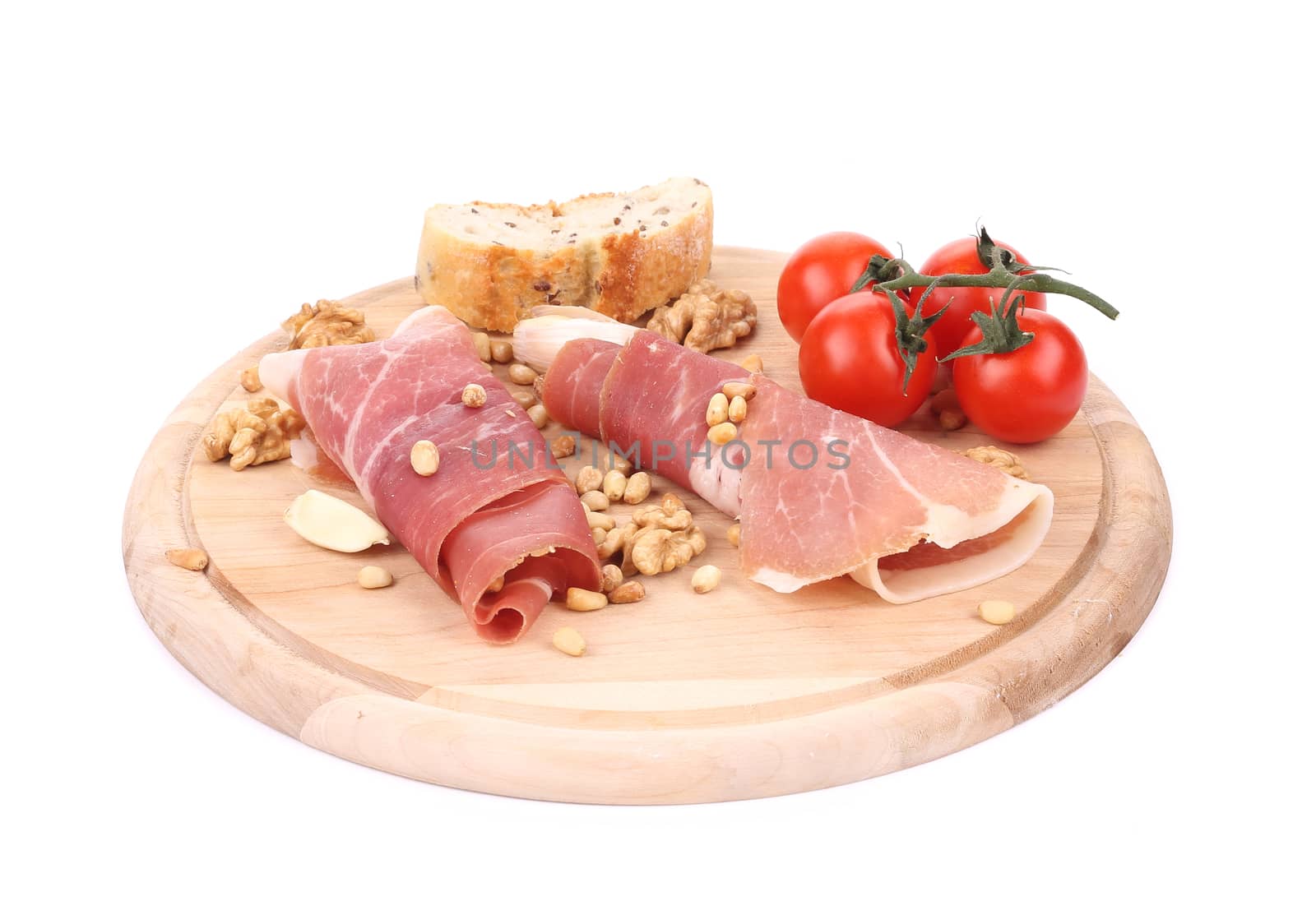 Composition of prosciutto on wooden platter. Isolated on a white background.
