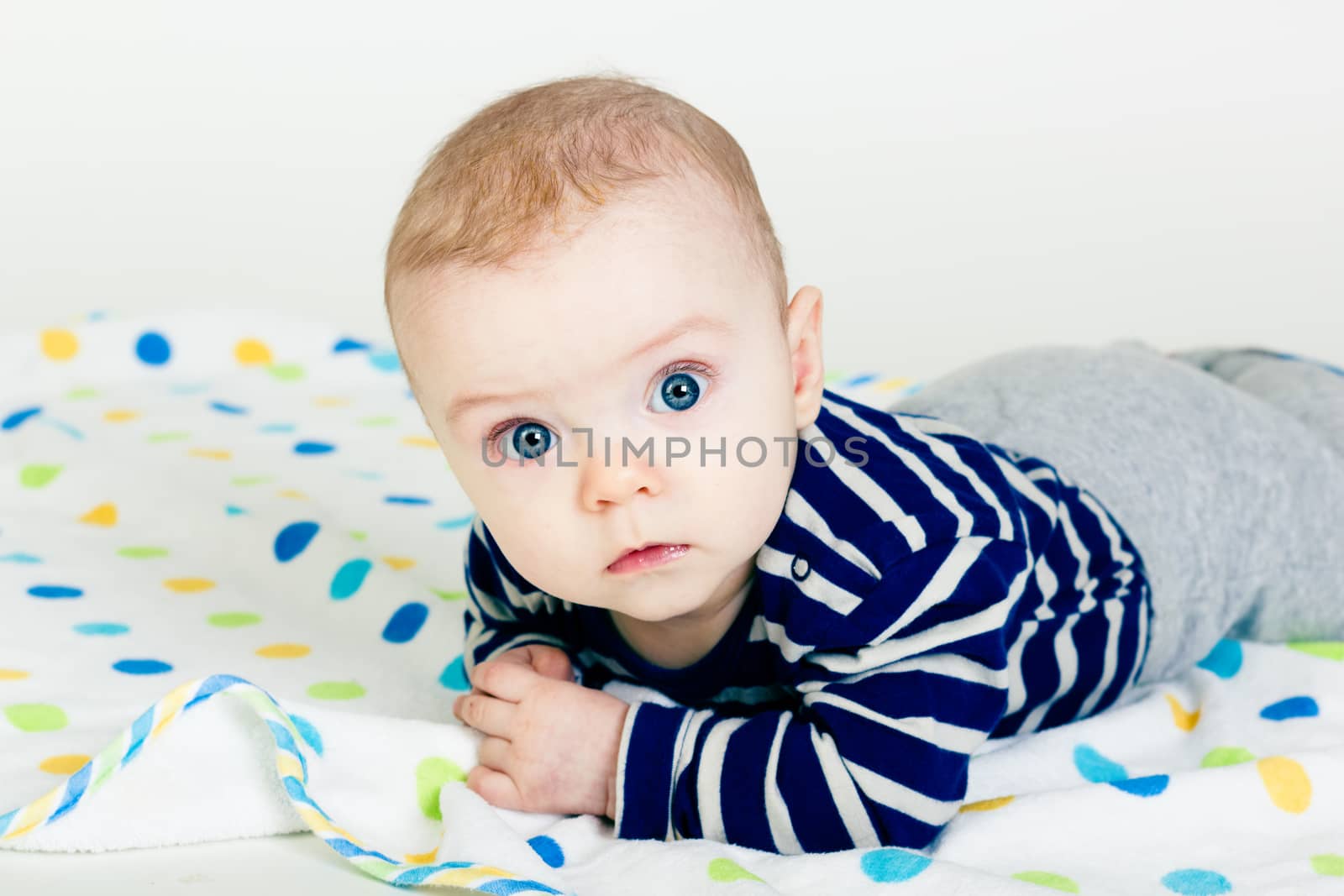 Portrait of a cute baby in striped clothes lying down on a blanket