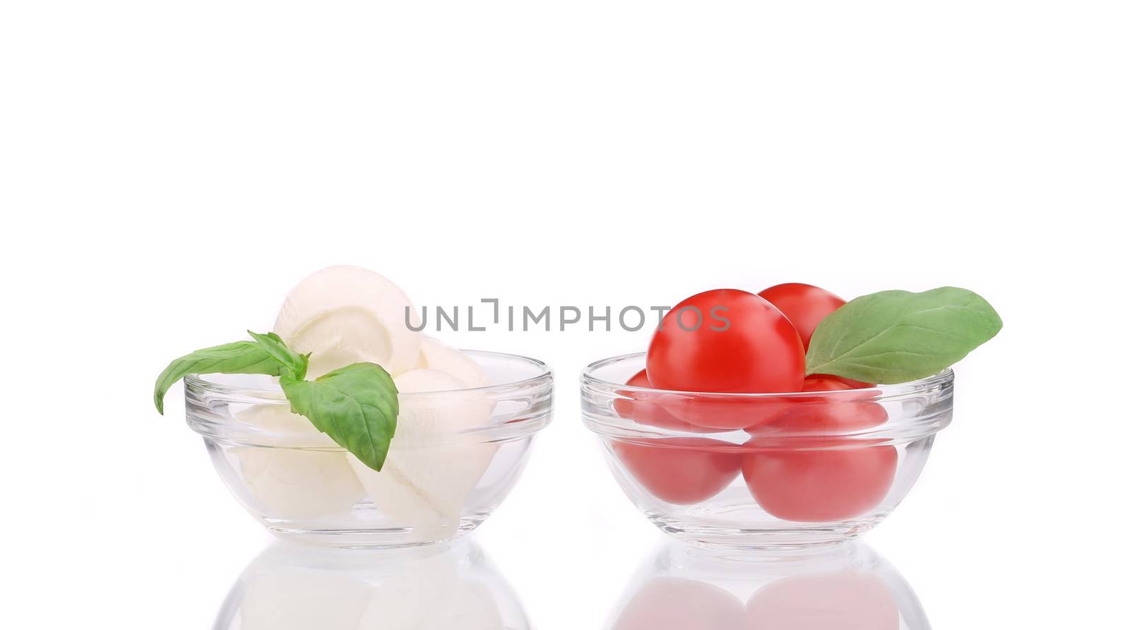 Mozzarella and tomatoes in glass bowl. by indigolotos