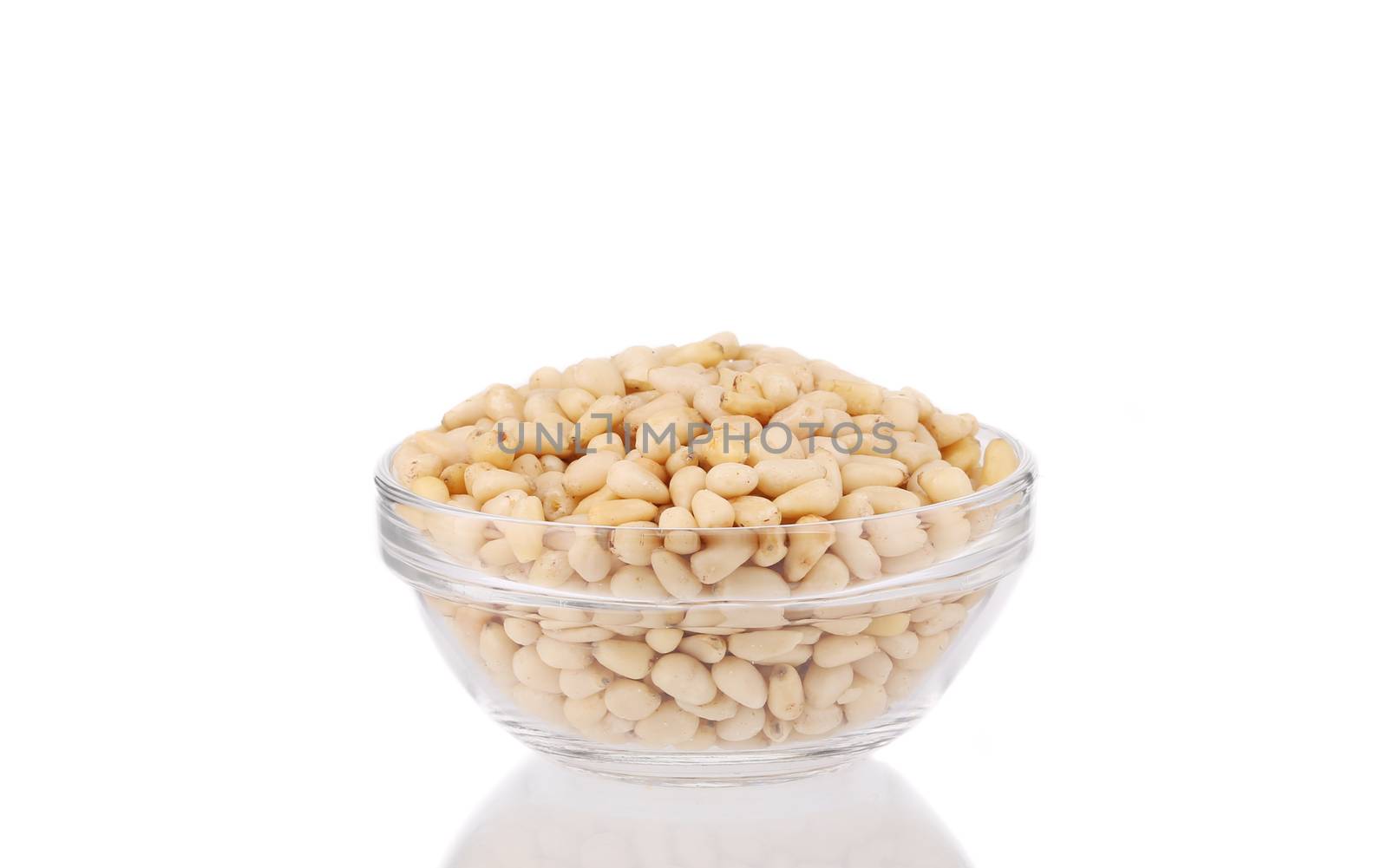 Glass bowl with tasty pine nuts. Isolated on a white background.
