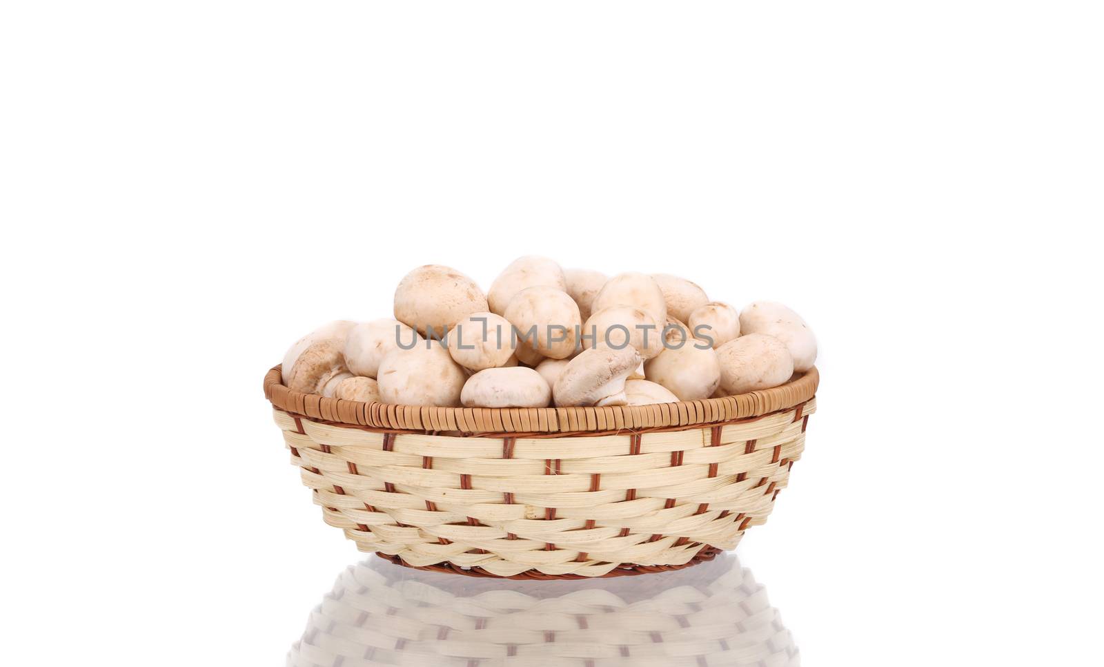 Wicker basket with champignon mushrooms. Isolated on a white background.