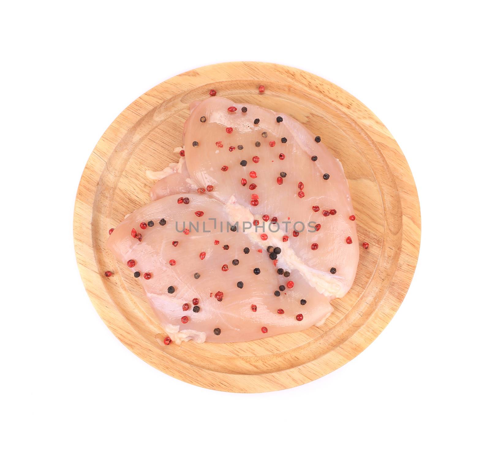 Raw chicken breast on wooden platter. Isolated on a white background.