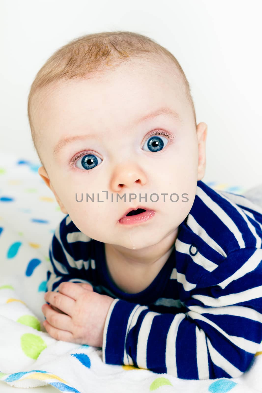 Portrait of a cute baby in striped clothes lying down on a blanket