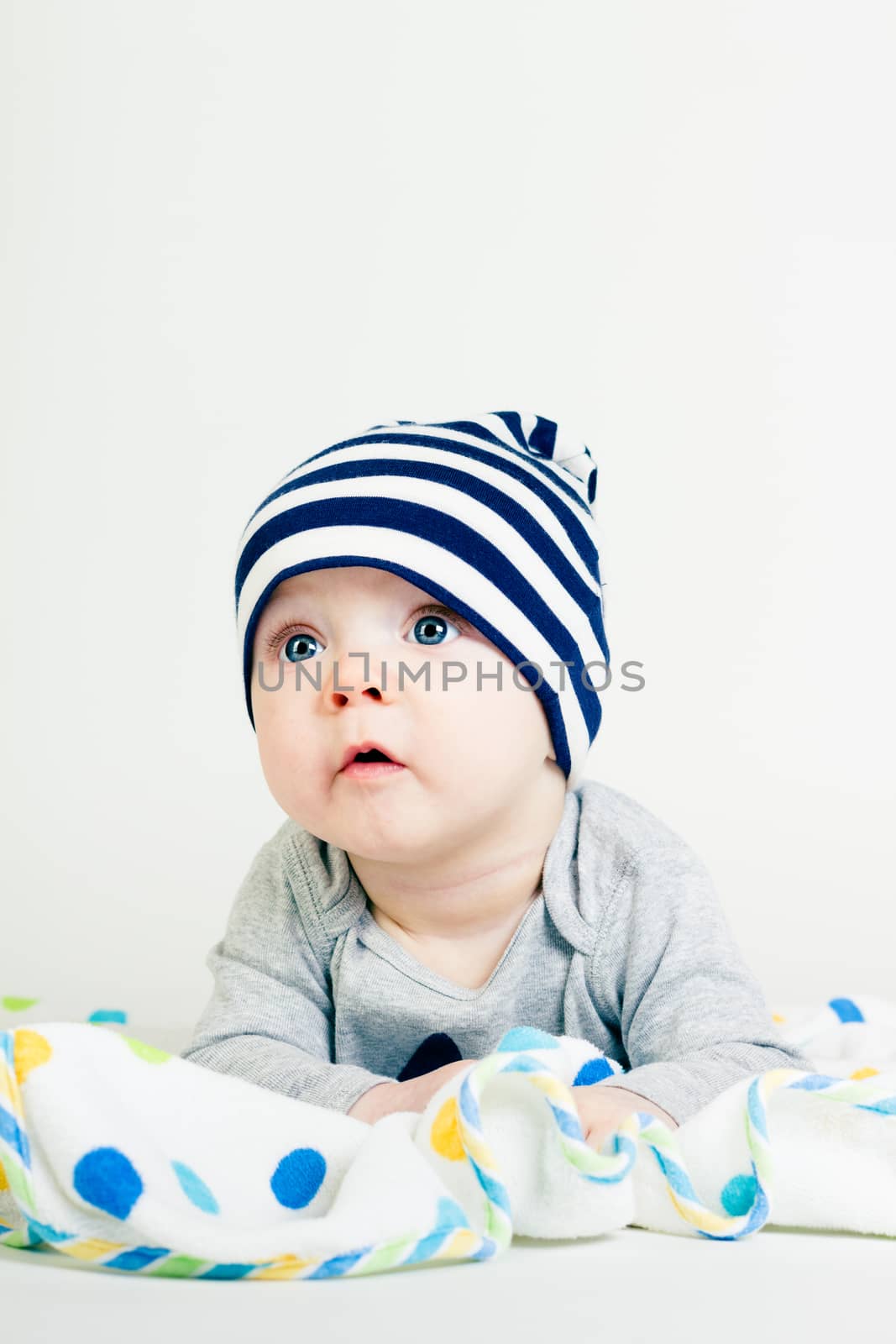 Portrait of a cute baby in striped hat lying down on a blanket