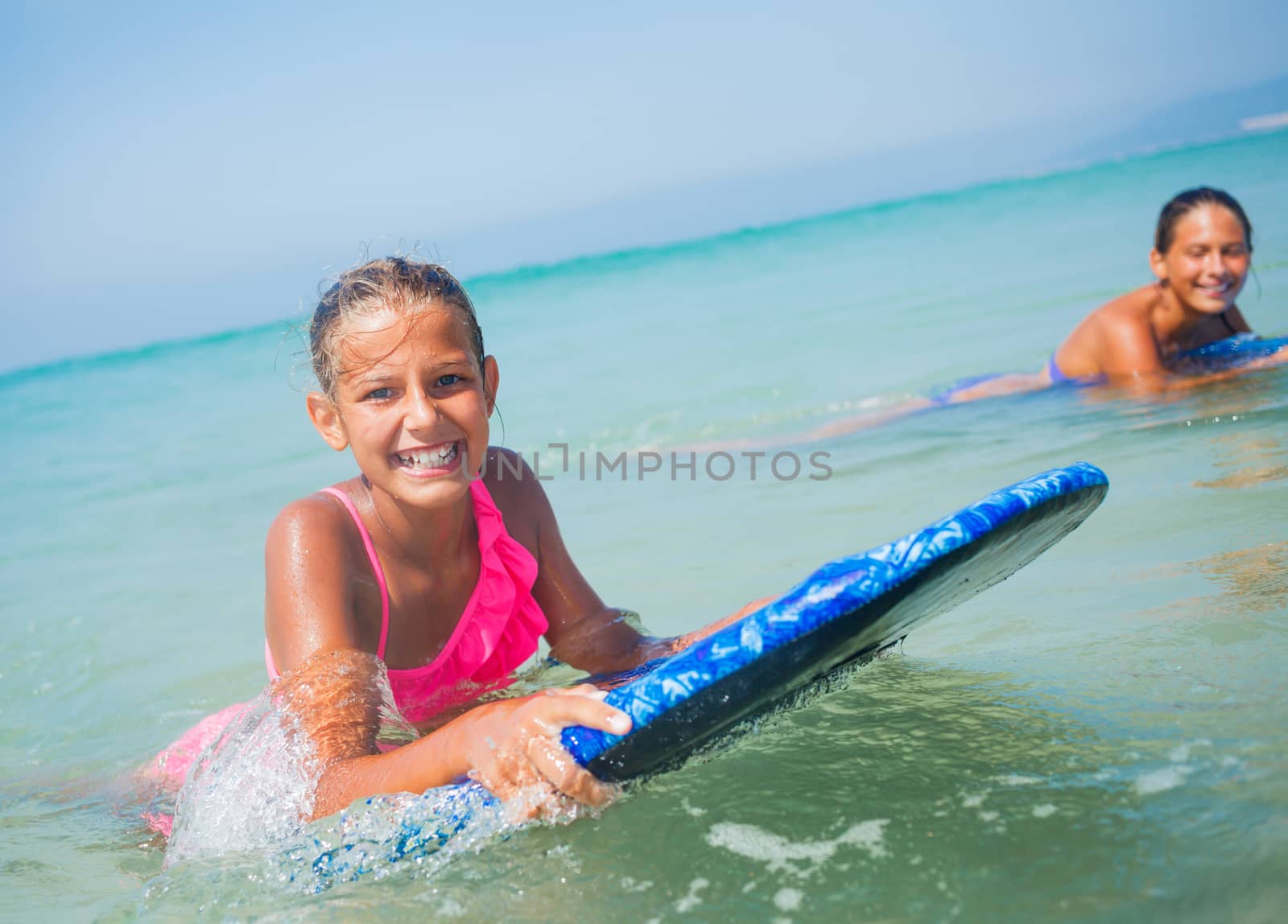 Summer vacation - Happy cute girls having fun with surfboard in the ocean