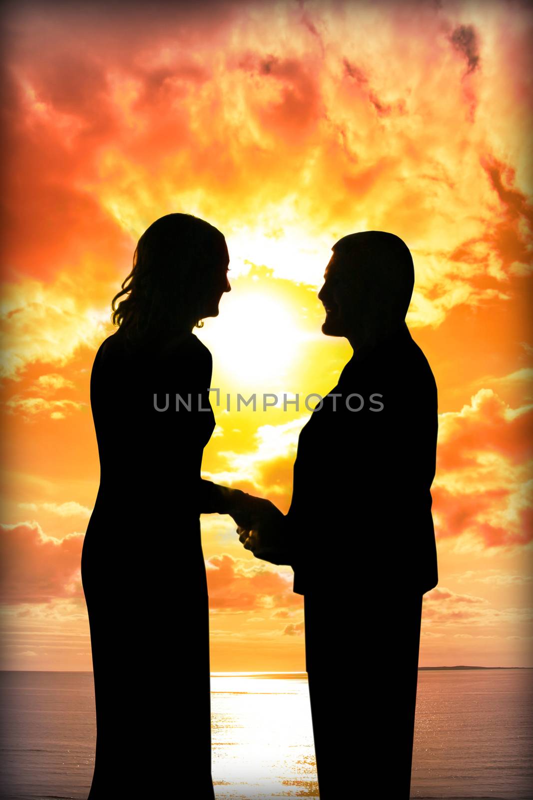 young loving couple holding hands in silhouette at sunset gazing into each others eyes