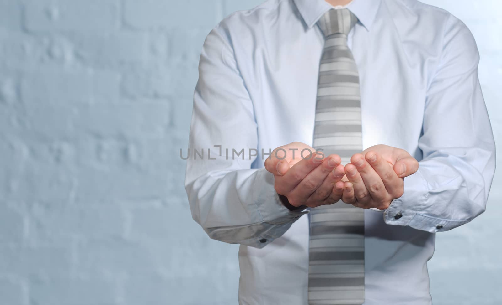 Businessman holding imaginary idea in hands by alistaircotton