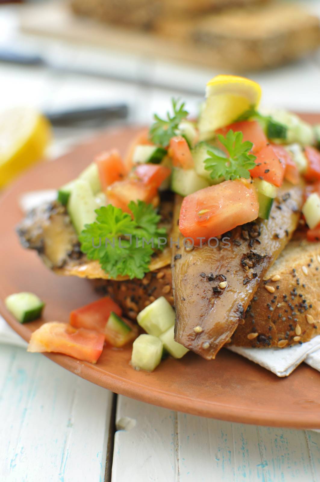Smoked mackerel fish with freshly chopped cucumber and tomato topping on a thick slice of bread 