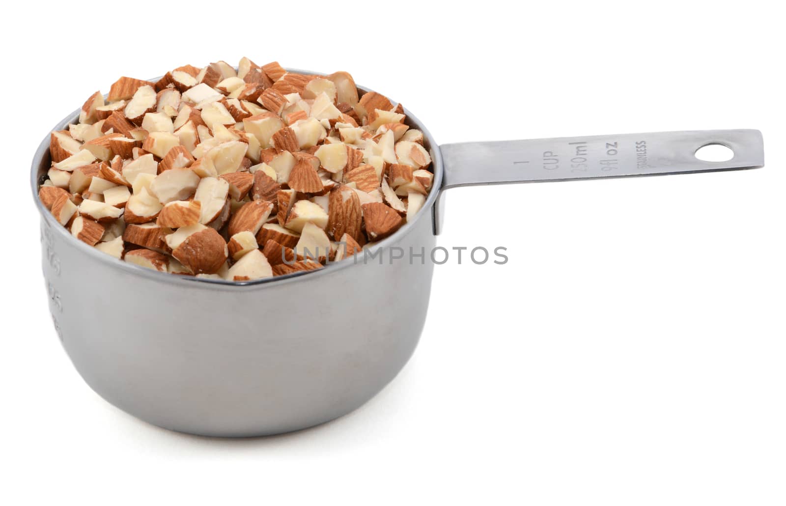 Chopped almonds presented in an American metal cup measure, isolated on a white background