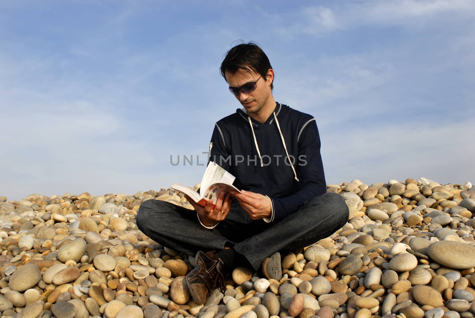 young man with a book at the beach