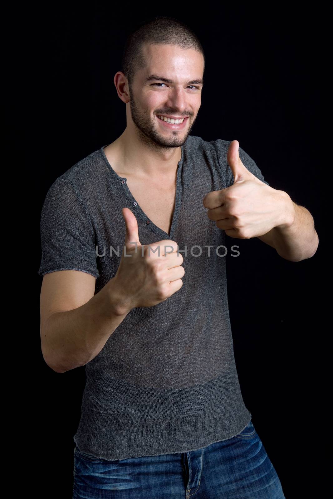 young casual man going thumbs up on a black background