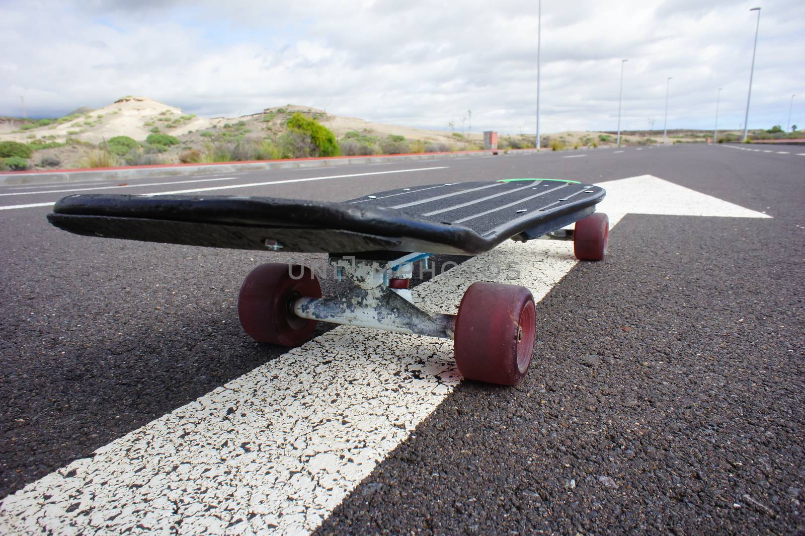 Vintage Style Longboard Black Skateboard on an Empty Asphalt Desert Road