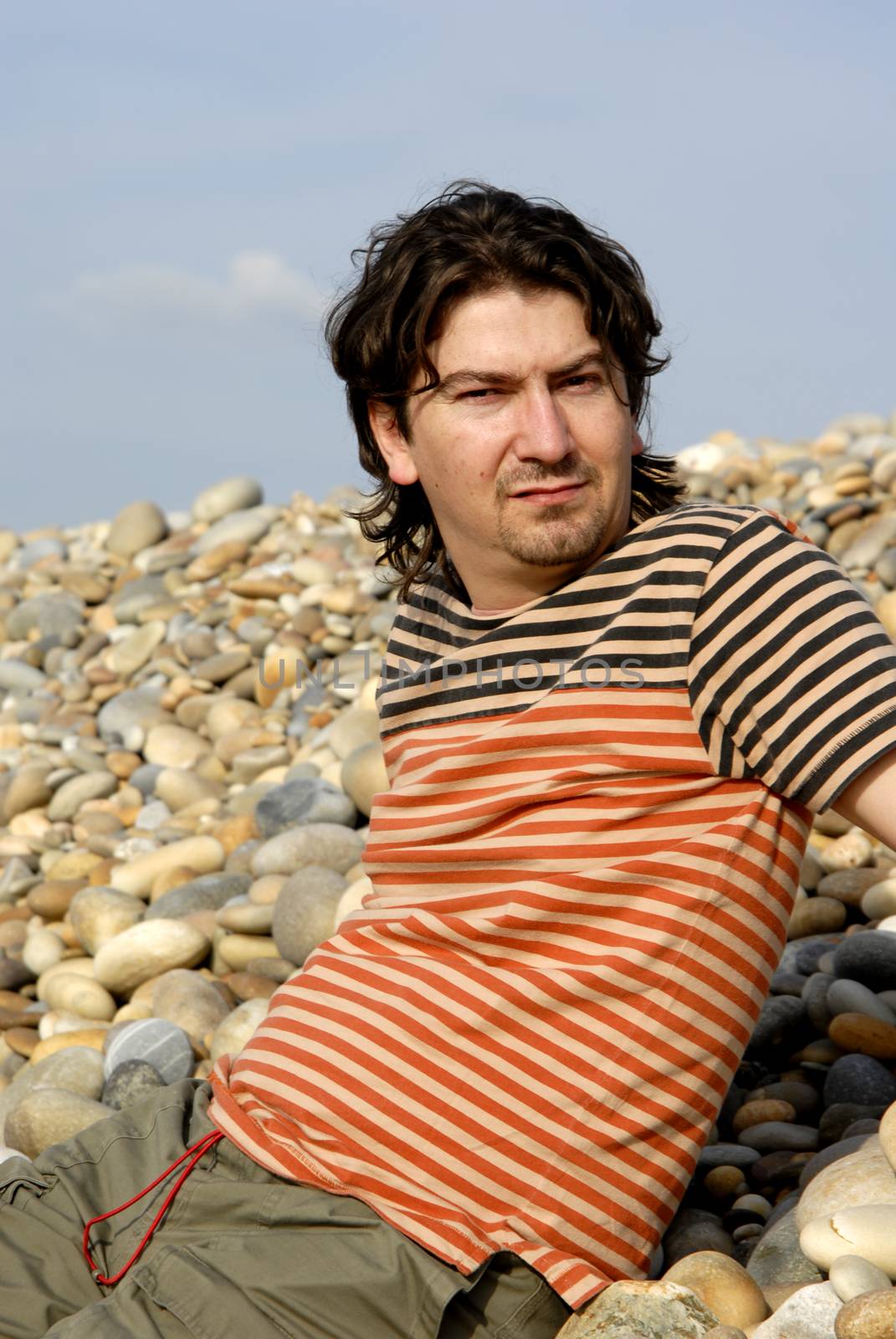 young casual man at the beach stones