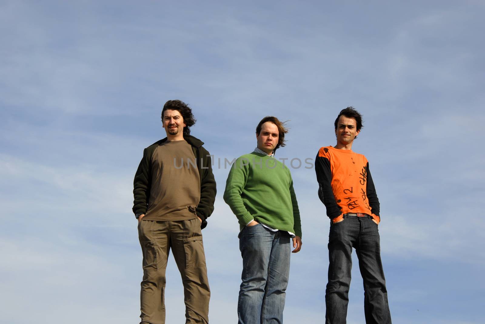 three casual young men with the sky as background