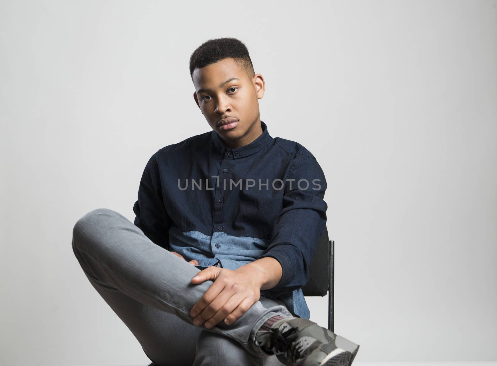 Portrait of handsome dark skinned male model wearing casual clothes against white background